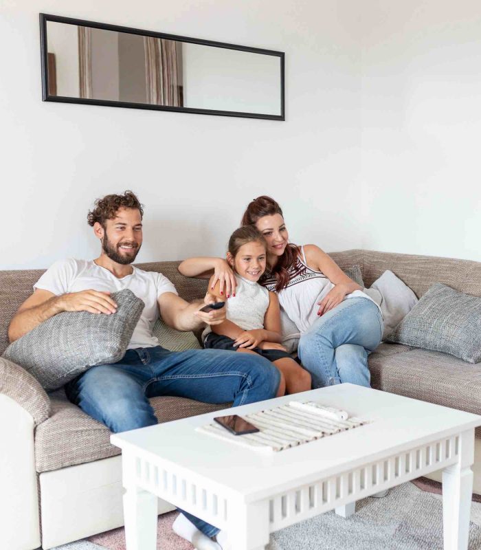 Family sitting on a couch watching TV.