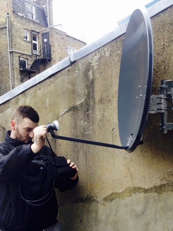 TV engineer aligning a 60cm satellite dish for European TV.